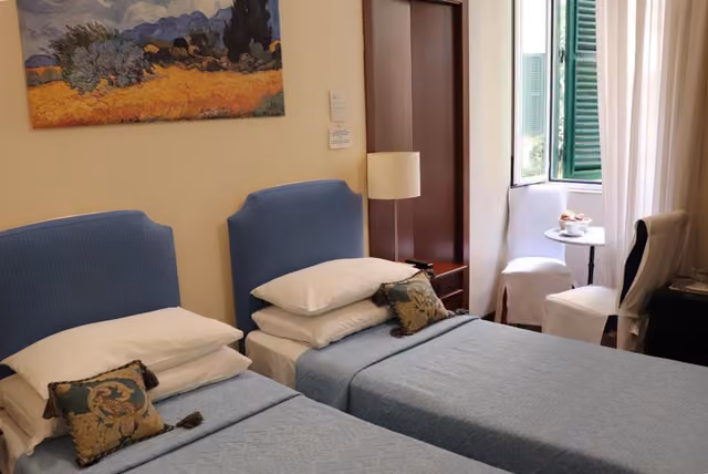 Camera tripla con due letti e quadro sulla parete al The Center of Rome Bed and Breakfast